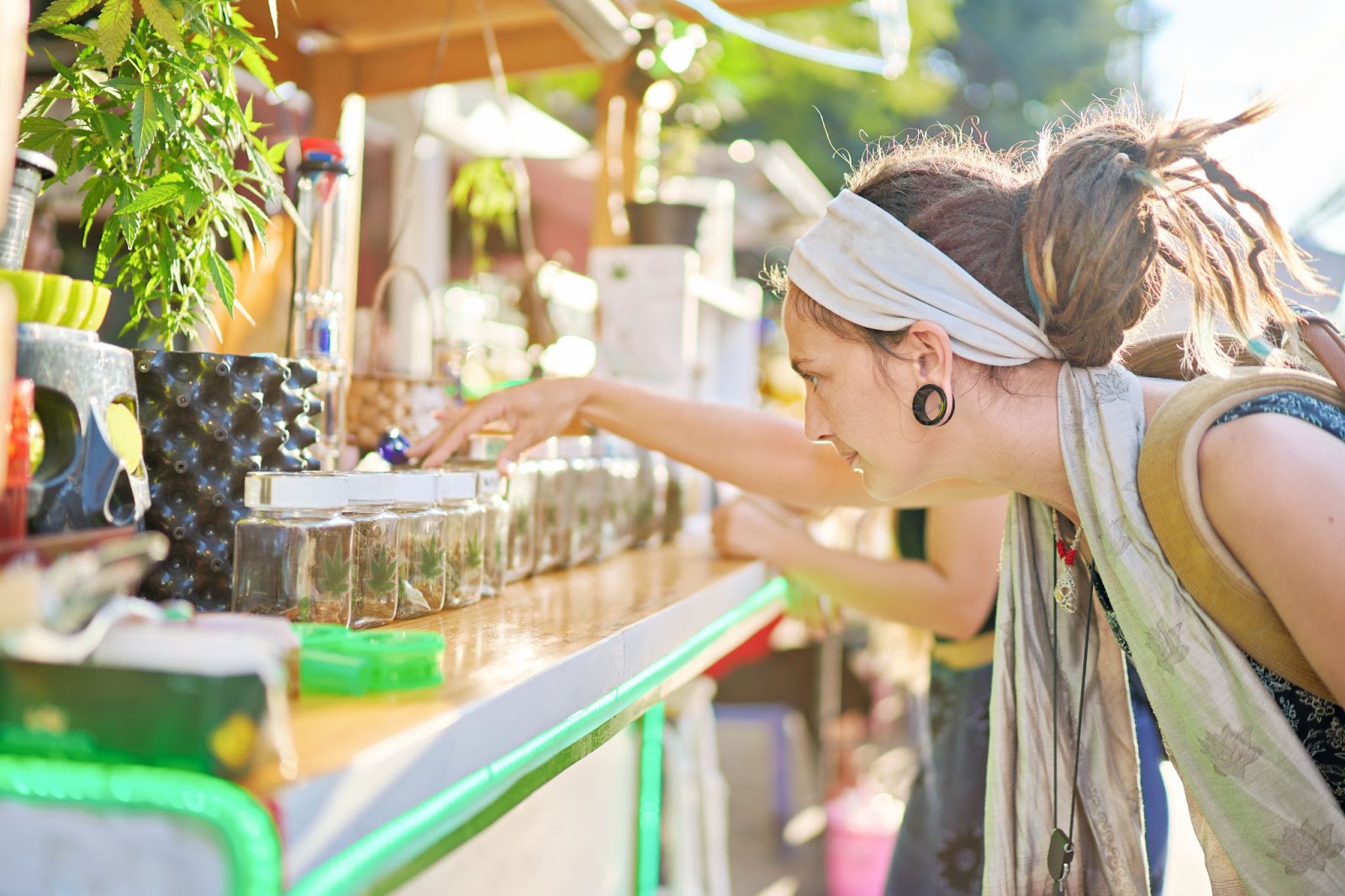 Femme examinant des produits de cannabis sur le stand d'un festival, mettant en valeur l'expérience d'achat interactive.