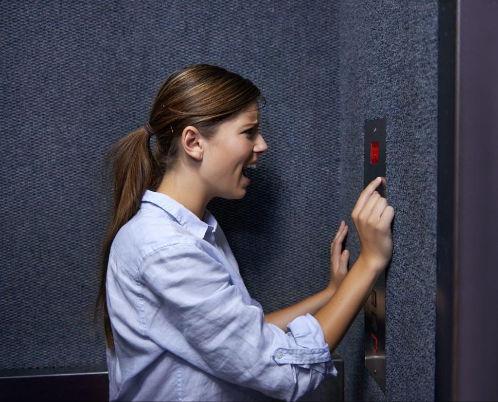 Woman pressing emergency button in apartment elevator.