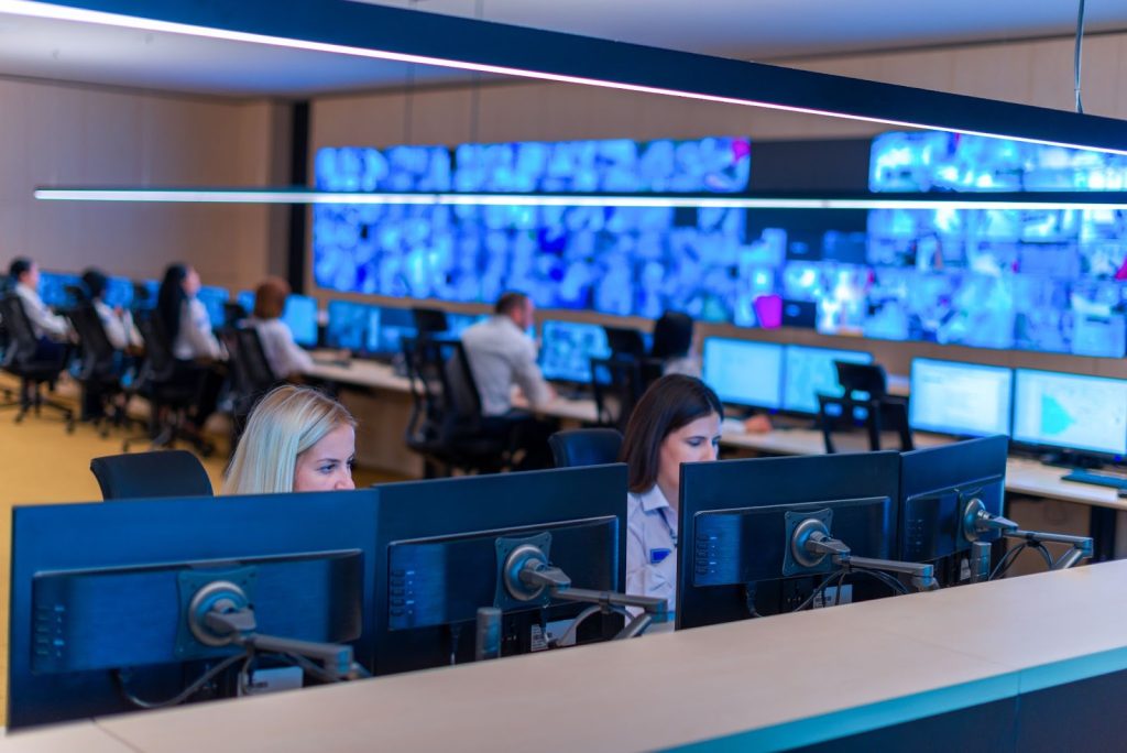 Security operators attentively monitor surveillance screens in a modern control room.