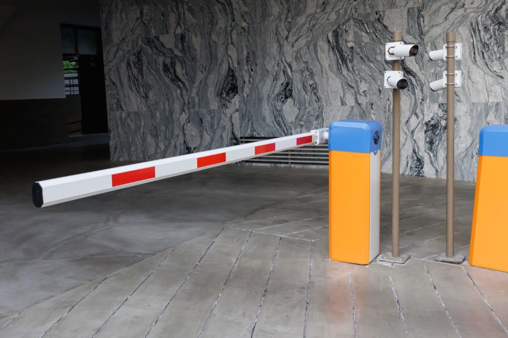 Caméras à balles surveillant un portail pour véhicules avec un bras de barrière.