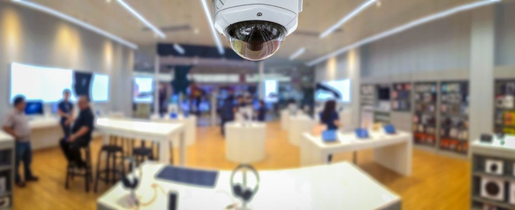 Overhead CCTV camera surveilling a retail store interior with customers.