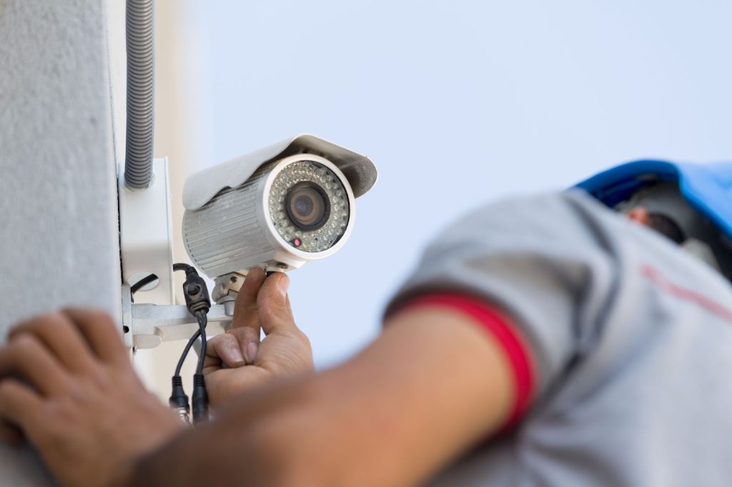Technician installing a CCTV camera on a wall for enhanced security.