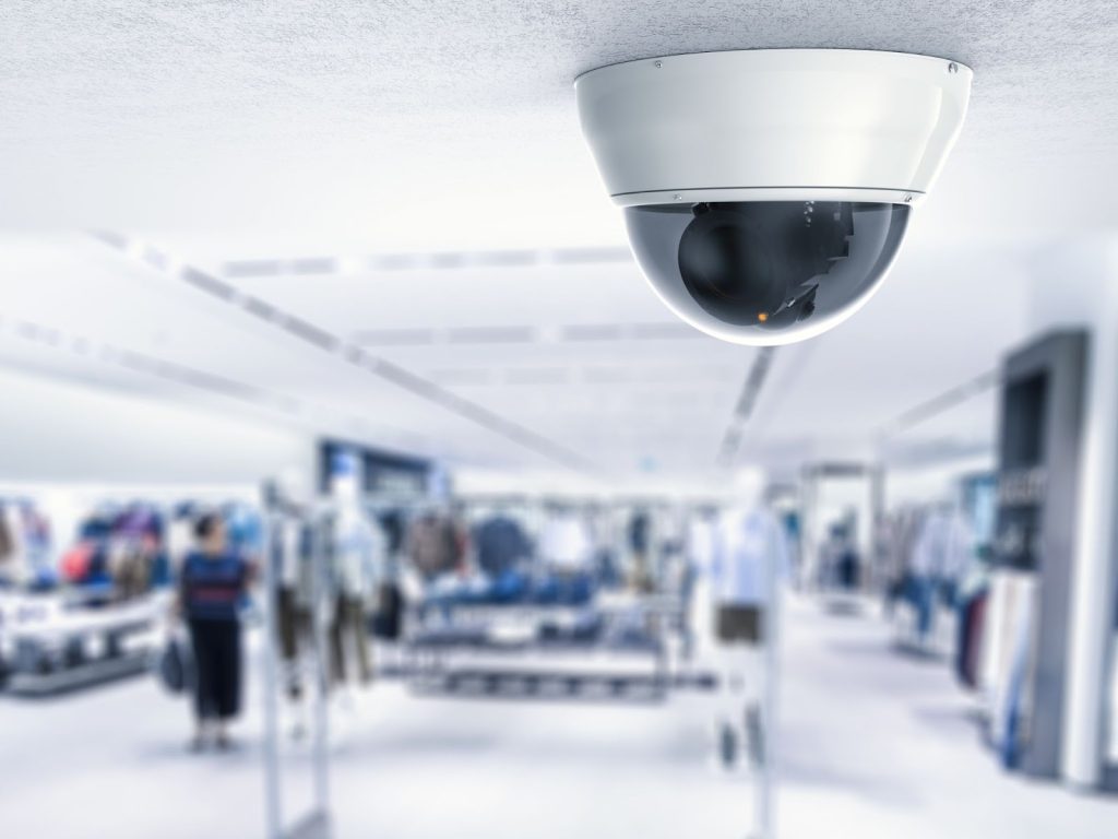 security camera mounted on a ceiling overseeing a retail store.