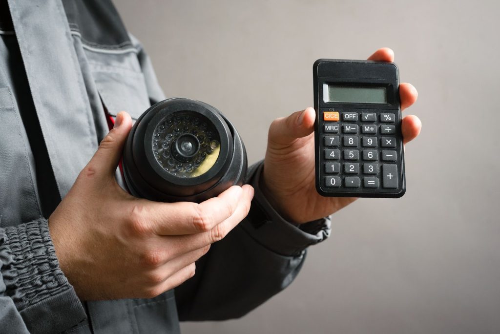 Technician holding a CCTV camera and calculator.