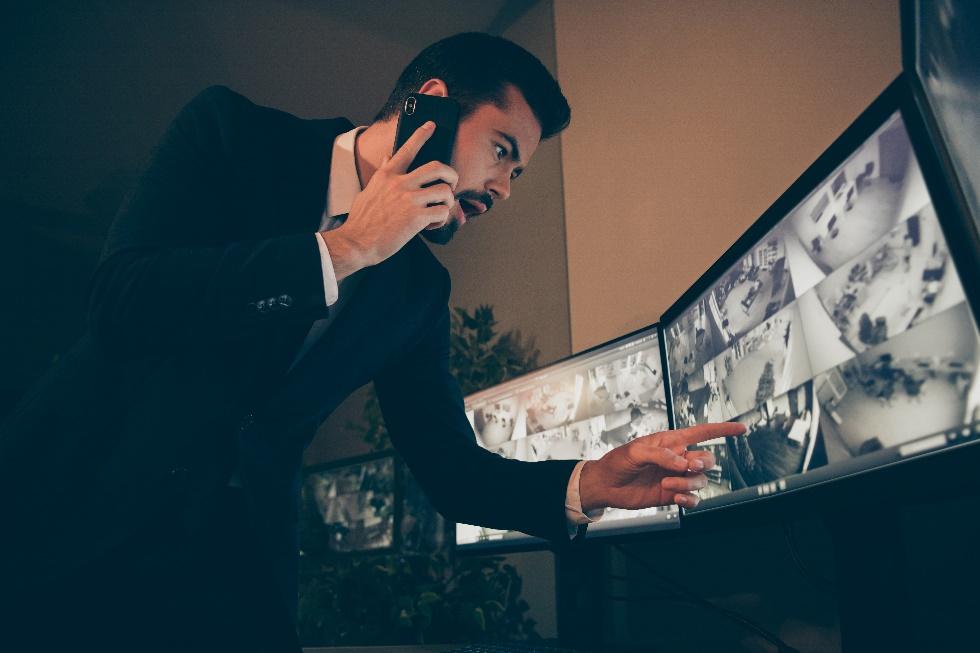 Homme d'affaires surveillant plusieurs caméras de sécurité.