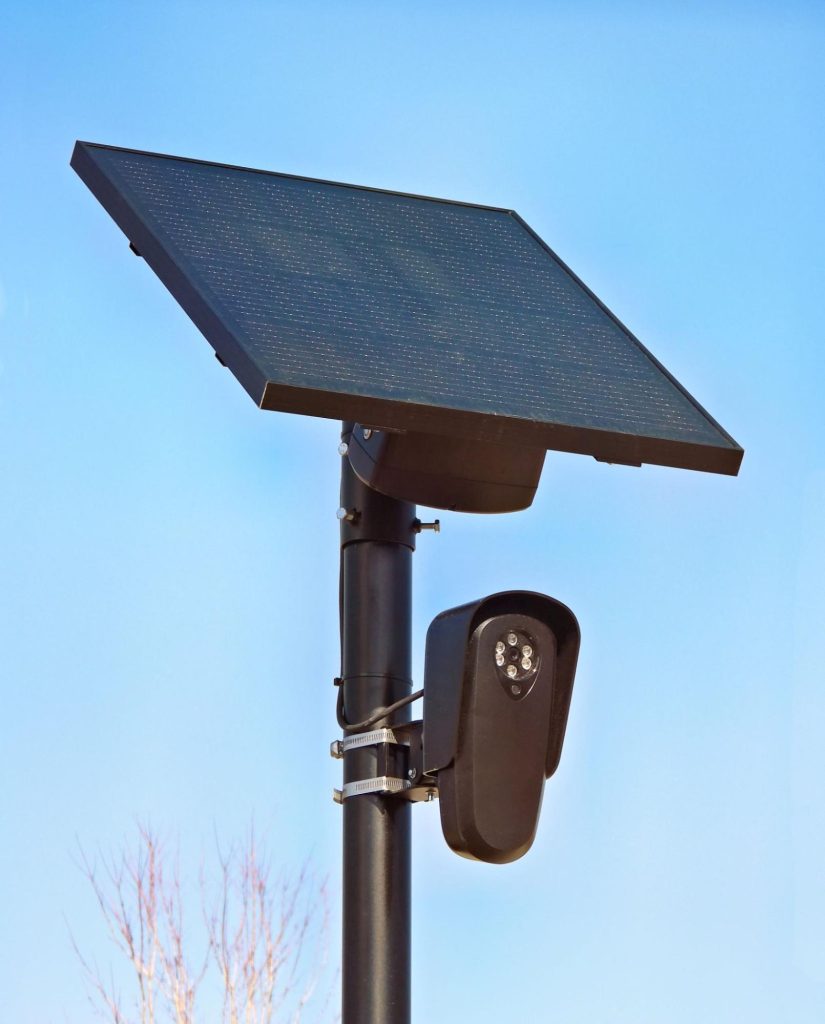 Panneau solaire alimentant une caméra de sécurité extérieure dans un ciel dégagé.
