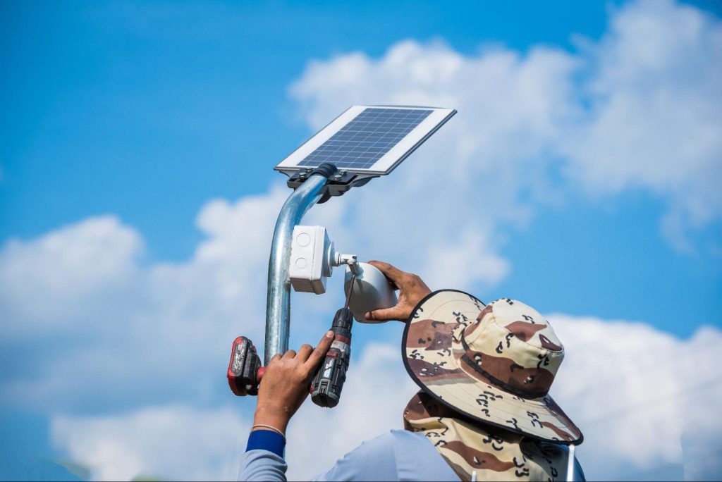 Technicien installant une caméra de sécurité solaire sur un poteau.