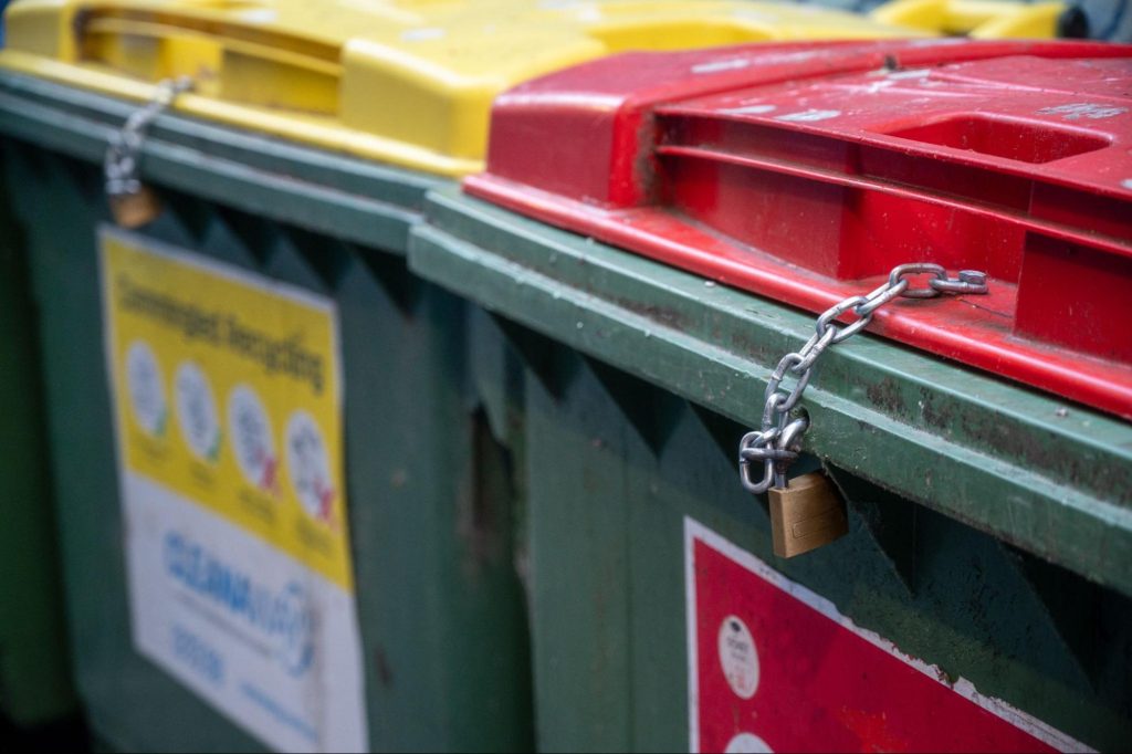 Des bennes de recyclage fermées à clé et sécurisées par des chaînes.