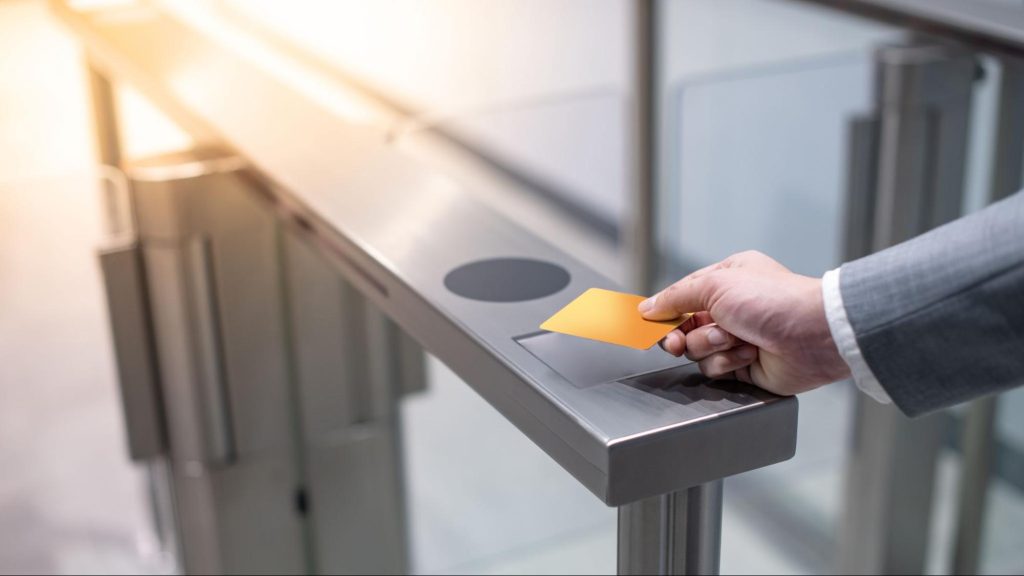 Hand using access card at a gate security system for controlled entry.