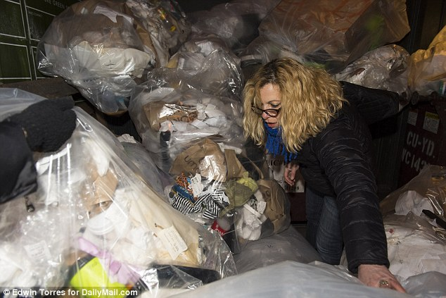 Femme fouillant des sacs de vêtements dans une benne à ordures.