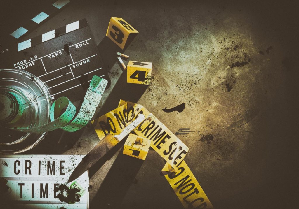 Crime scene setup with markers, tape, and a film clapperboard on a dark surface.