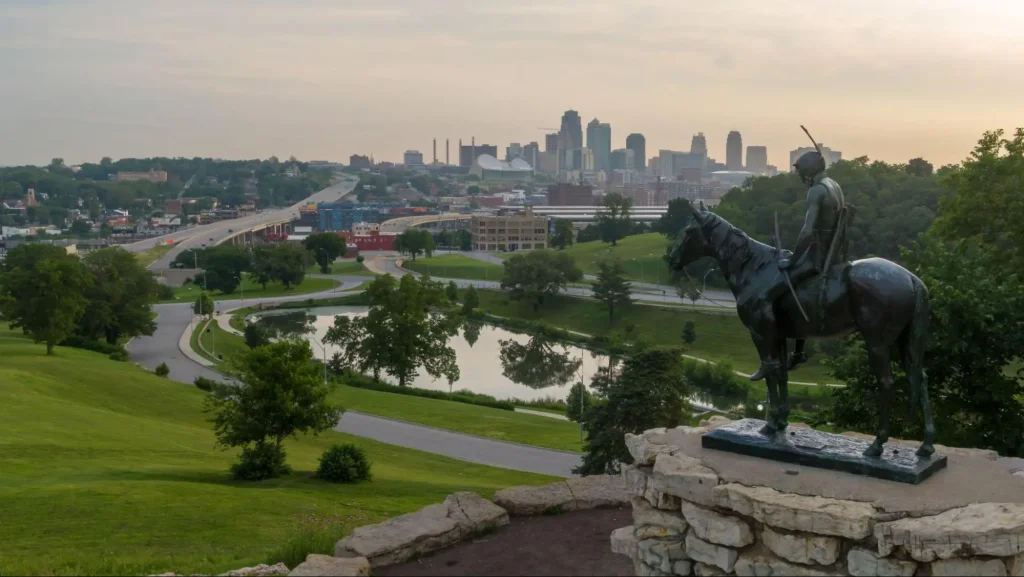 Statue d'un Amérindien à cheval surplombant l'horizon de Kansas City, symbolisant la vigilance.