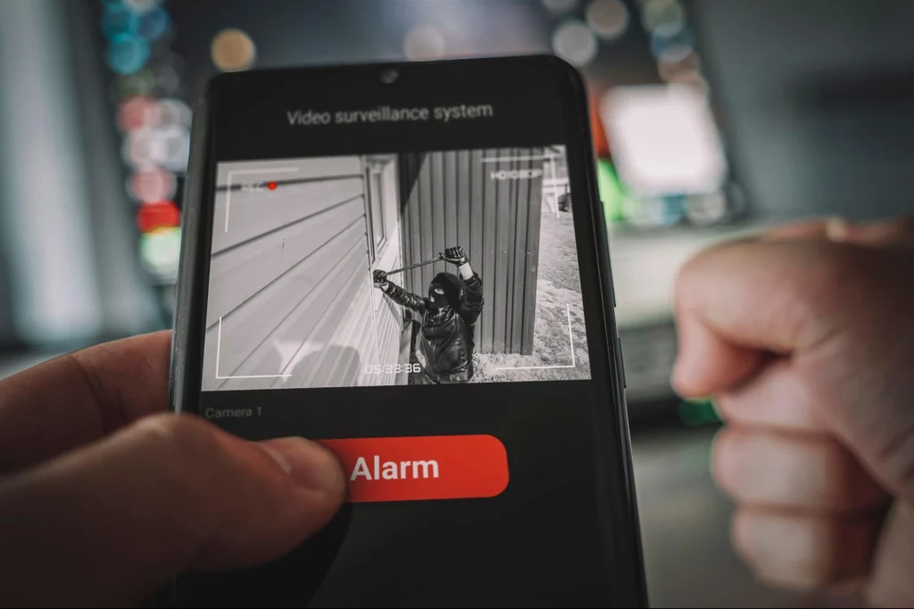 Hand pressing alarm button on mobile showing a security breach on construction site.