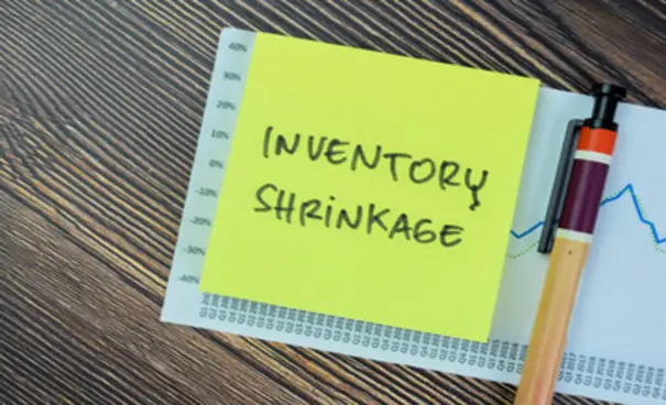 Sticky note labeled Inventory Shrinkage placed on a financial report with graph