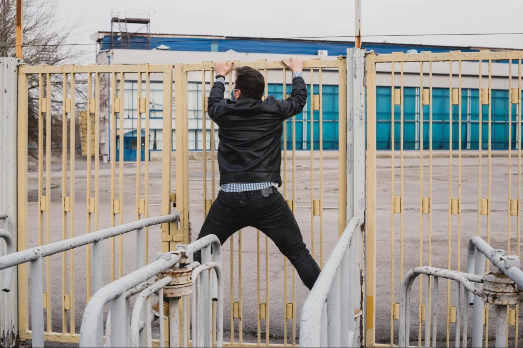 Unauthorized person climbing construction site fence, highlighting security risks.