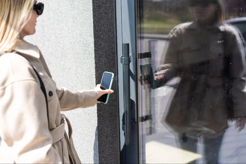 A woman using a smartphone to unlock a secure door via access control.