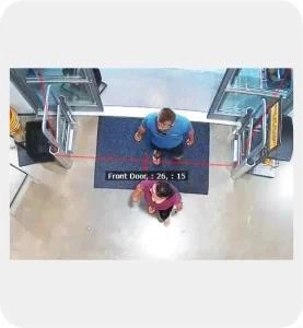 Une caméra de surveillance alimentée par l'IA suit deux personnes à l'entrée d'un immeuble.